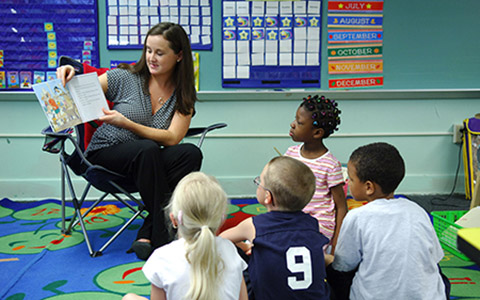 A teacher reads a picture book to a class of young students