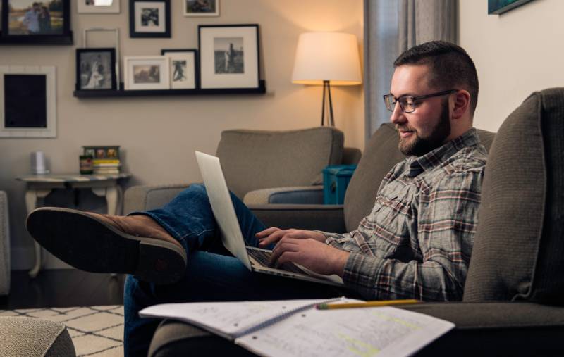 male student with laptop sitting on couch