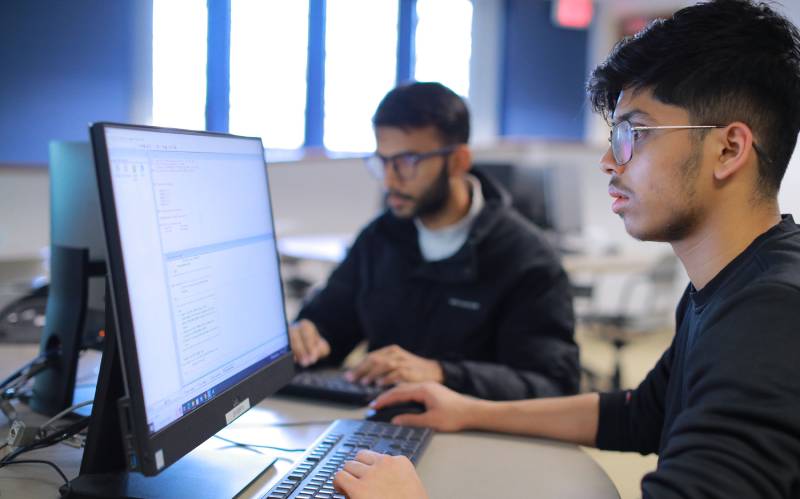 student analyzes program code on computer monitor