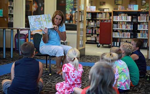 Teacher showing a book to a group of small children at the library
